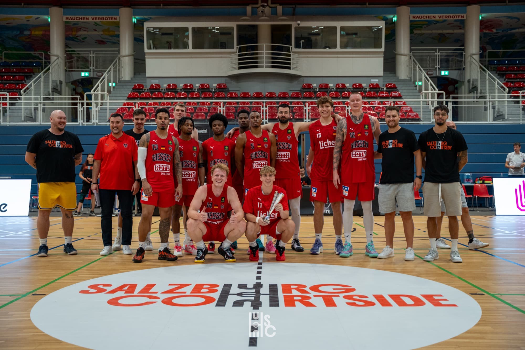 Die Gießen 46ers in Rot mit Staff und Pokal am Mittelkreis